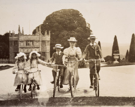 Black & white archive photograph of four Agar-Robartes children on bicycles outside the Gatehouse at Lanhydrock, Cornwall