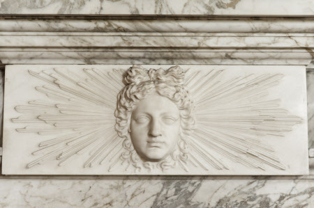The face of Apollo on the fireplace in the Library at Wimpole Hall, Cambridgeshire.