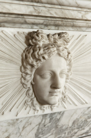The face of Apollo on the fireplace in the Library at Wimpole Hall, Cambridgeshire.